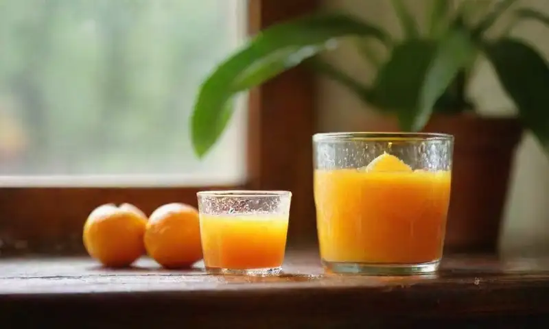 Una mesa de madera rústica, iluminada por la luz cálida del sol, con cáscaras de naranja, jugo brillante, aceite esencial, utensilios de cocina y una planta pequeña, todo en un ambiente acogedor y natural