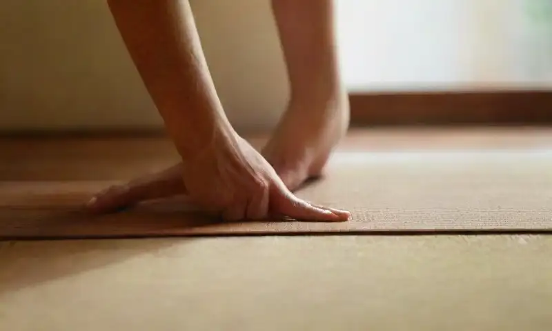 Una figura femenina delgada se encuentra relajadamente sobre una estera de yoga