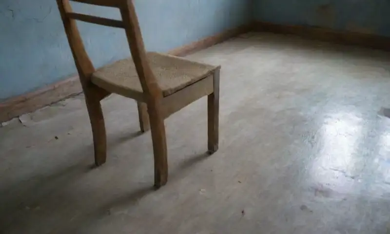 Una habitación oscura y desoladora, con paredes deterioradas y un ambiente de sufrimiento palpable