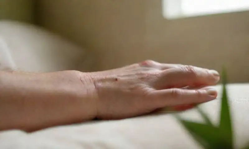 Una mano humana reposa sobre una almohada suave en la luz de la mañana, creando una atmósfera de calma y tranquilidad