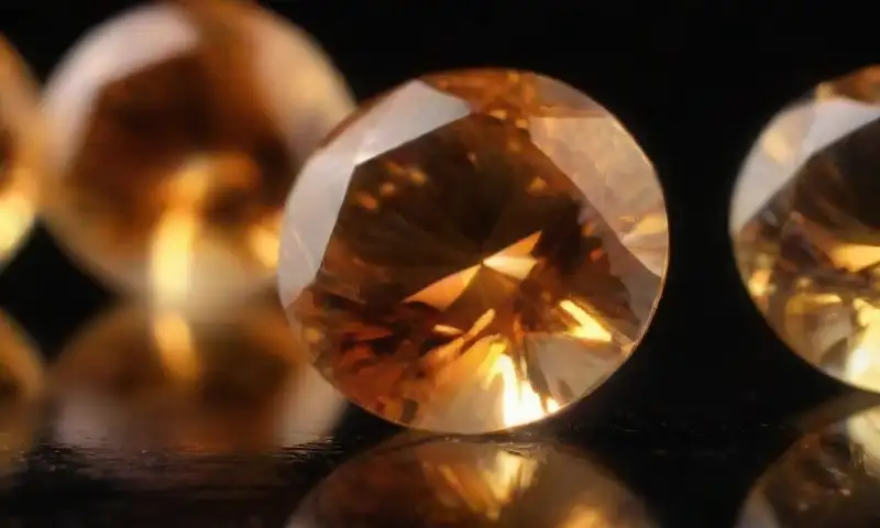 Una imagen en primer plano de un brillante topacio dorado, con facetas pulidas que reflejan luz y muestran inclusiones internas, sobre un fondo de terciopelo oscuro