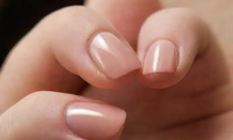 Primer plano realista de una mano con uñas bien cuidadas, detalles sutiles y un ambiente sereno